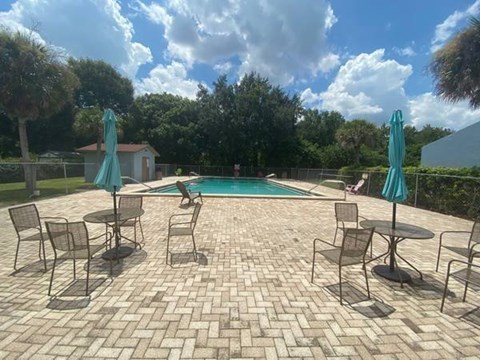A patio with a table and chairs overlooking a pool.