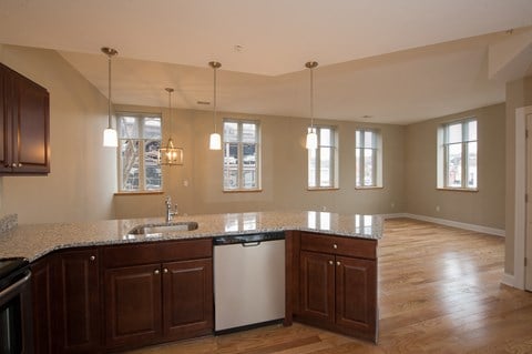 an open kitchen and living room with wood floors and granite counter tops