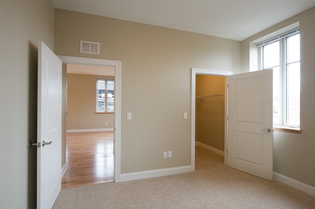 an empty living room with a door to a hallway and a closet