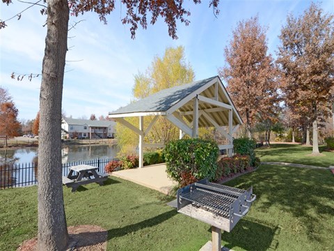 a park with a bench and a pavilion near a lake