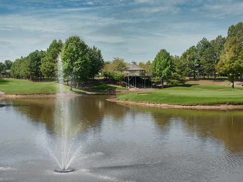 a fountain in the middle of a pond in a park