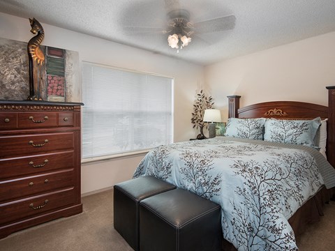 a bedroom with a bed and a dresser and a ceiling fan