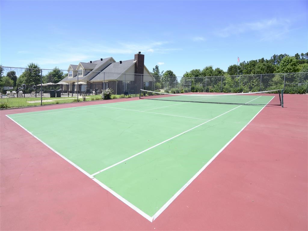 a tennis court with a house in the background