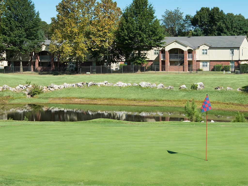 a golf course with a pond and a flag