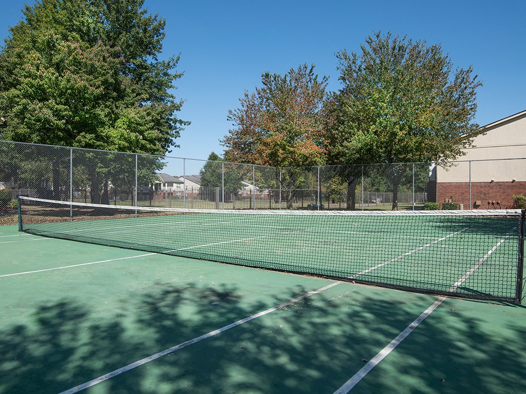a tennis court with trees and a building in the background