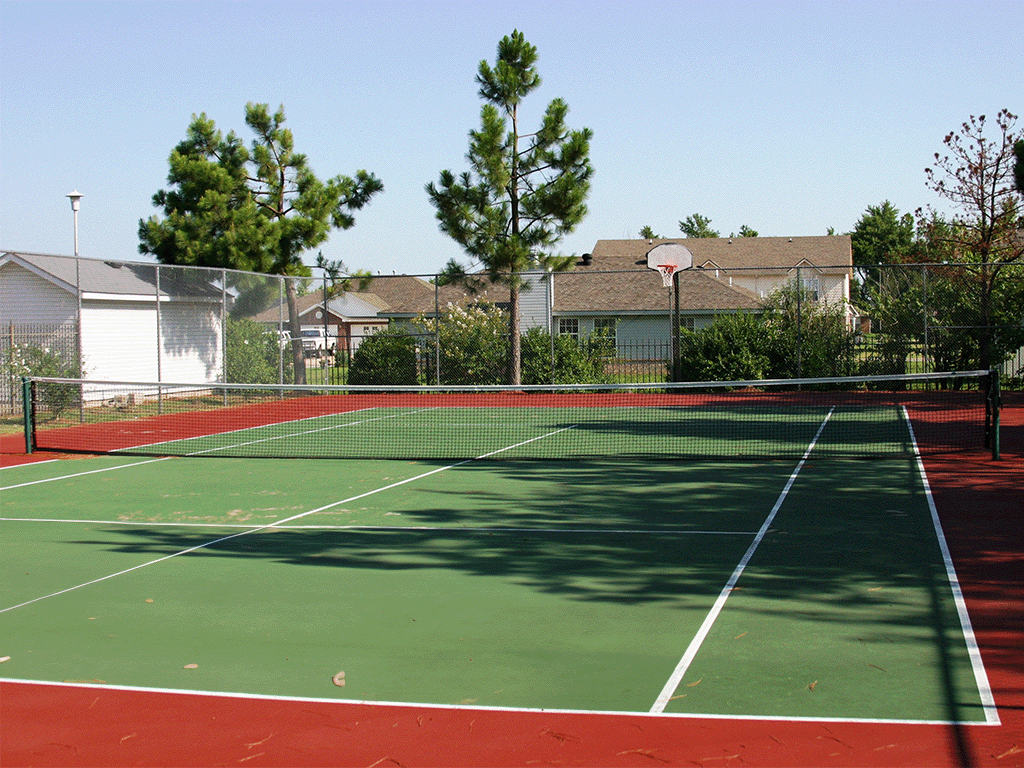 a tennis court with trees and houses in the background