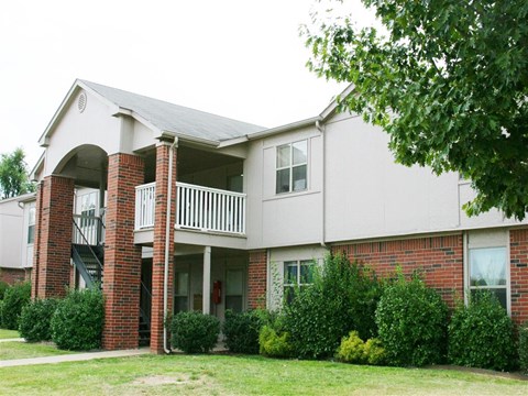 the exterior of an apartment building with a yard and a balcony
