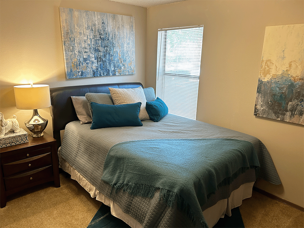 a bedroom with a bed and two paintings on the wall