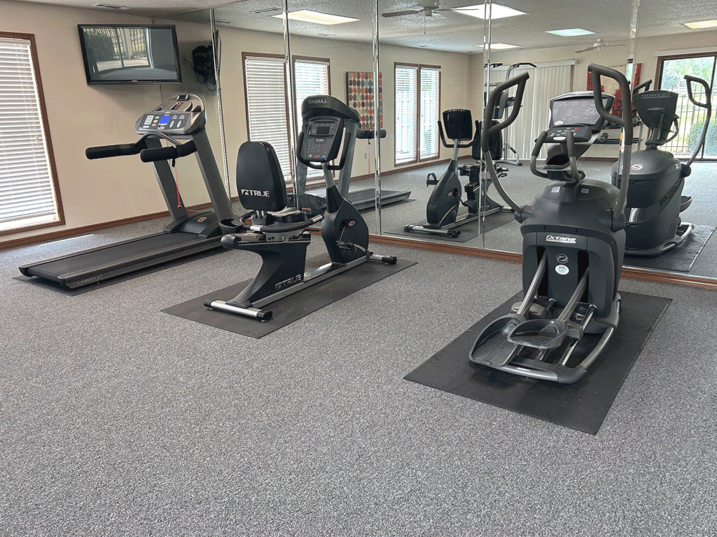 a gym with exercise machines and mirrors in a building