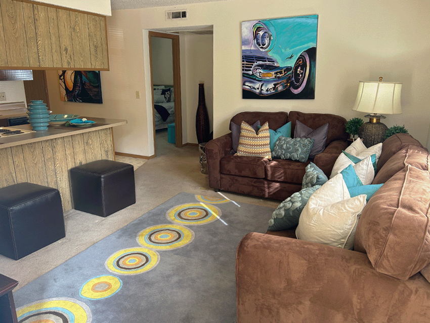 a living room with brown couches and a blue rug