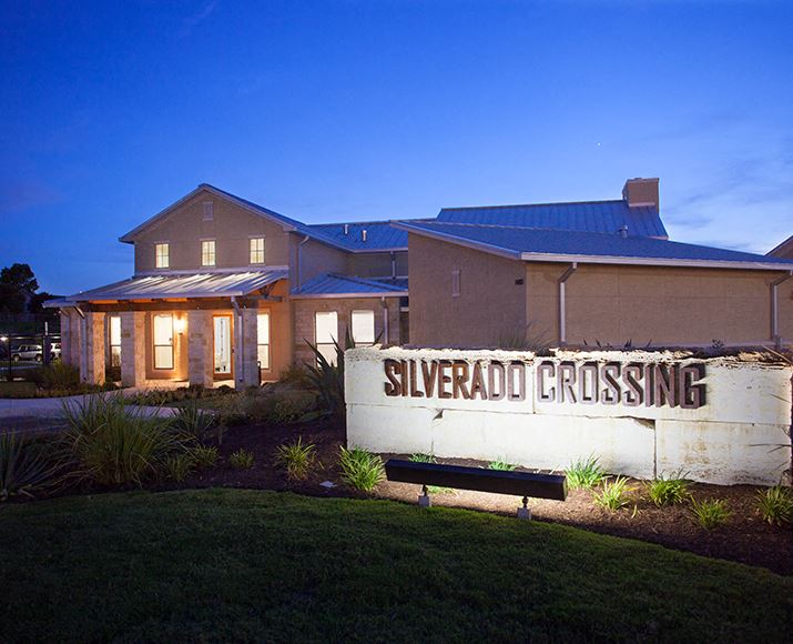 Evening entrance with office and monument sign Silverado Crossing Apartments For Rent  l Buda Texas 78610 - Photo Gallery 1