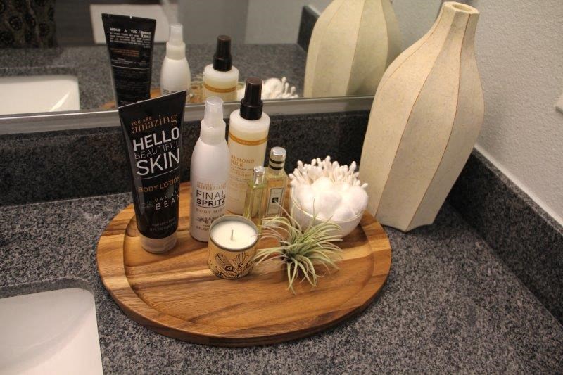 a bathroom counter with various toiletries on a wooden cutting board