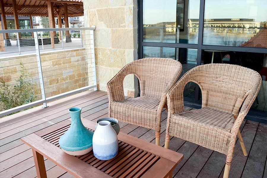 two chairs and a table with vases on a deck