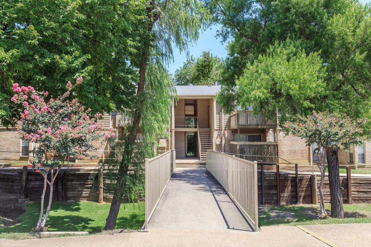 a bridge leading to an apartment building with trees