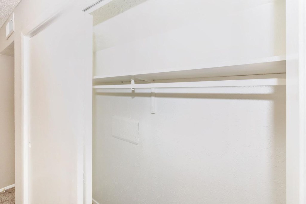 an empty closet with white walls and a white closet door