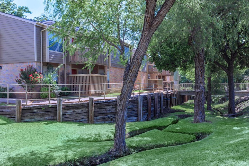 a yard with grass and trees in front of a building