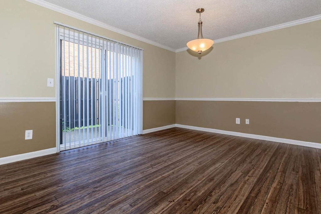 an empty living room with wood flooring and a sliding glass door