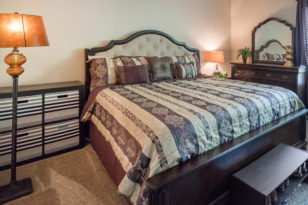 a bedroom with a bed and two night stands and a dresser