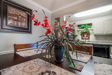 a dining room table with a vase of red flowers on it