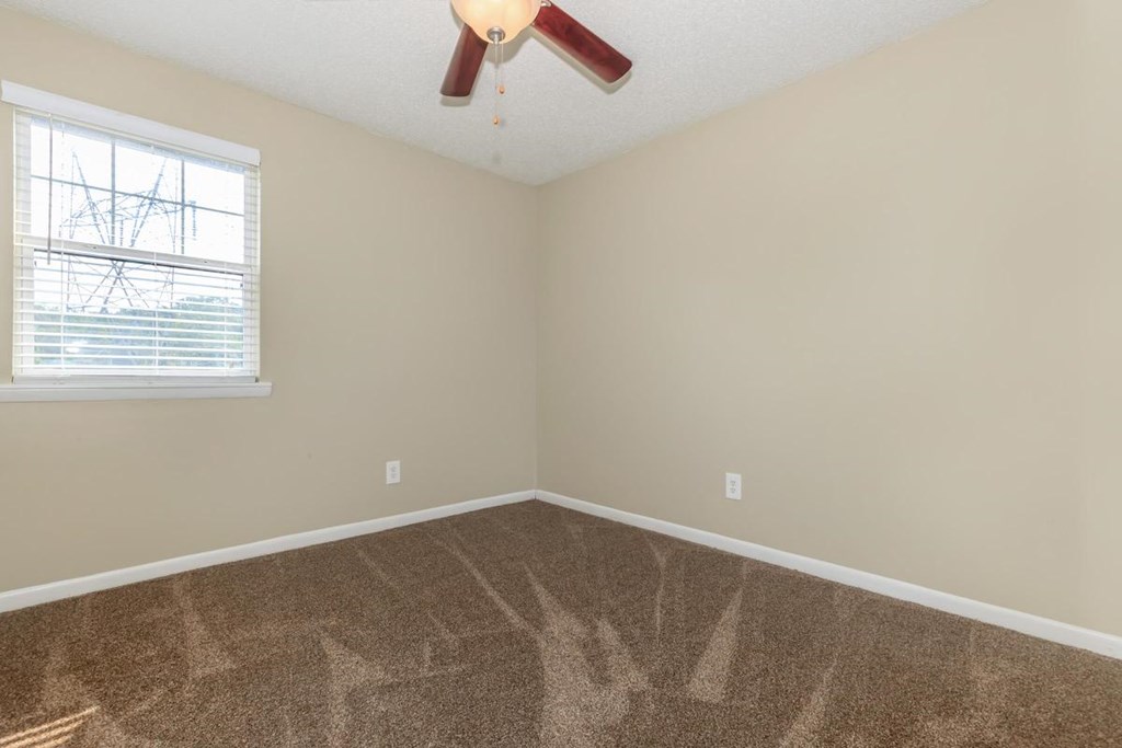 a bedroom with carpet and a window and a ceiling fan