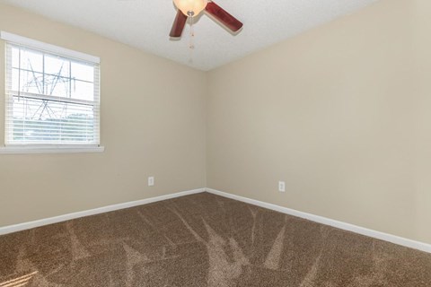 a bedroom with carpet and a window and a ceiling fan