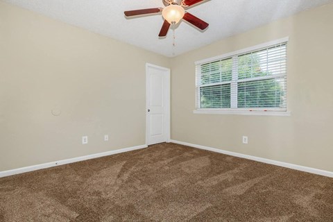 an empty room with a ceiling fan and a window