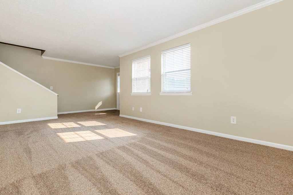 the living room and dining room of an empty home with carpet