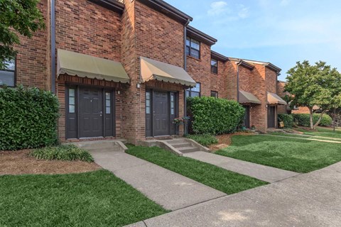 the front of a brick building with sidewalk and grass