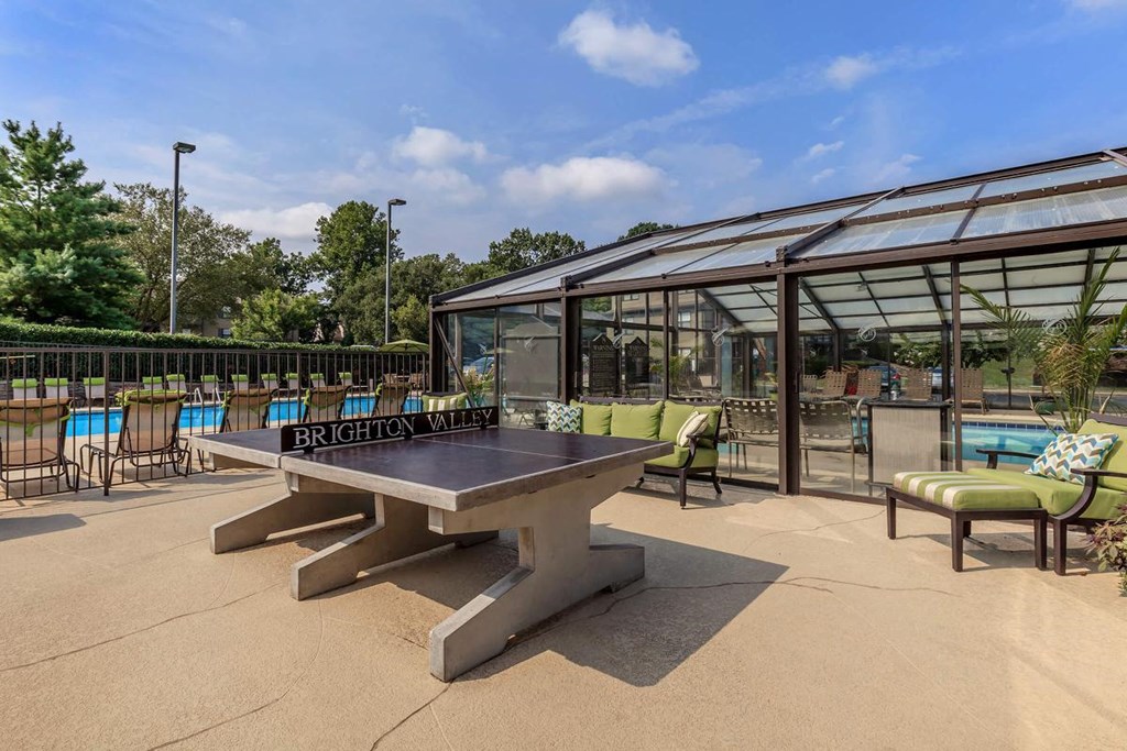 a patio with a ping pong table and chairs near a pool