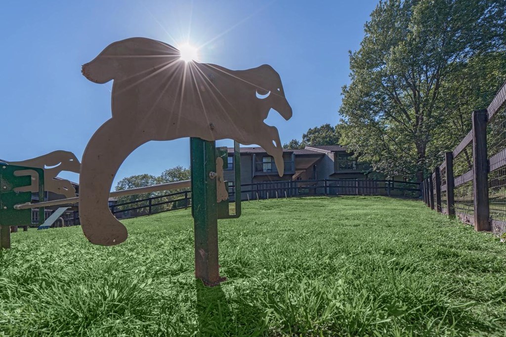 a wooden horse sculpture in a field with a house in the background