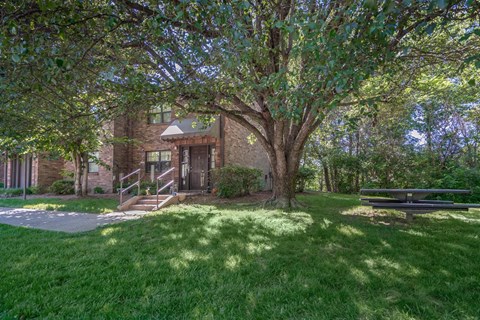 the front of a brick house with a tree in the yard