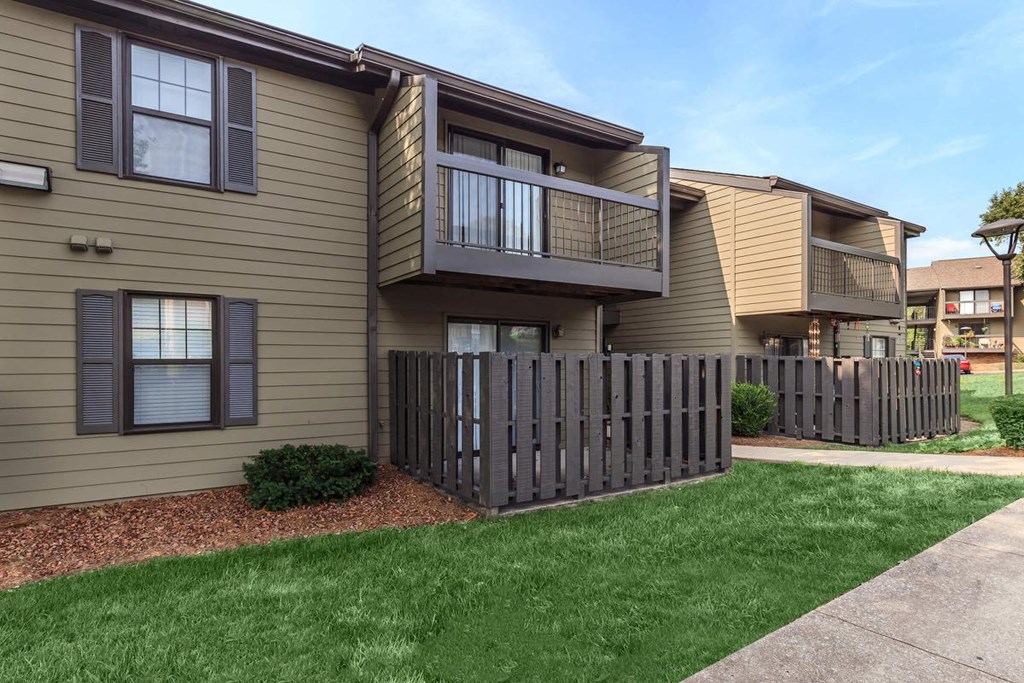 an apartment building with a yard and a fence