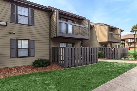 an apartment building with a yard and a fence