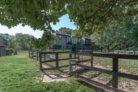 a fenced in dog park with a house in the background