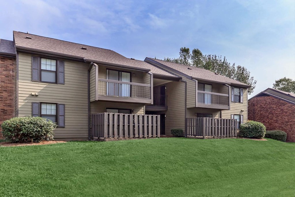 an apartment building with a lawn and a fence