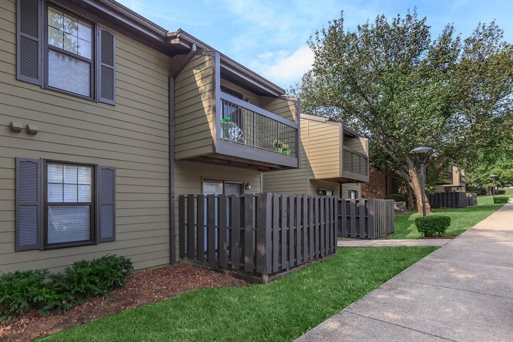 an apartment building with a sidewalk and a fence