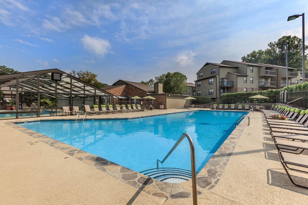 a swimming pool with chairs and a building in the background