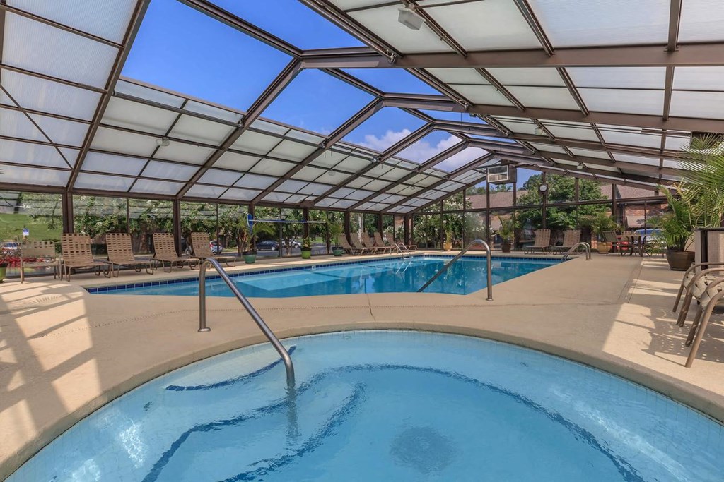 a pool with a hot tub under a glass roof