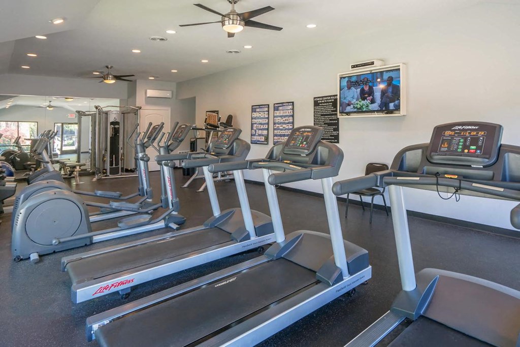 a gym with cardio equipment and a flat screen tv