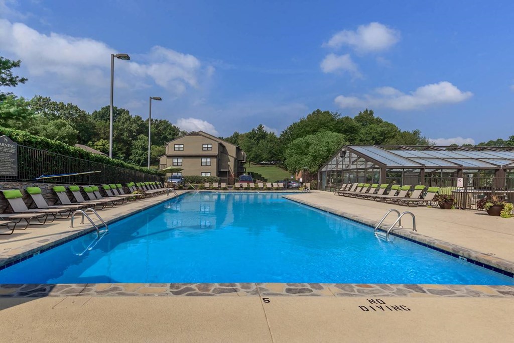 a swimming pool with chairs around it and a building in the background