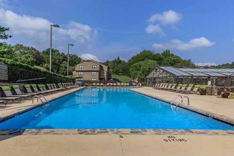 a swimming pool with chairs around it and a building in the background