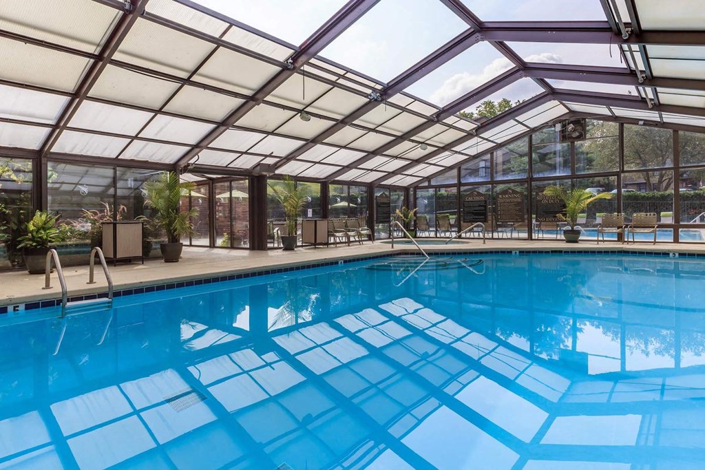 the pool is under a glass roof and next to a large window