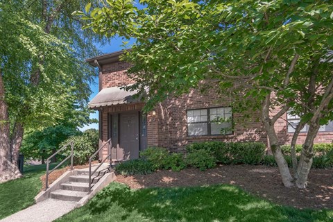 a small brick house with a tree in front of it