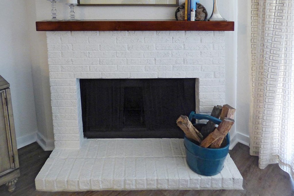 a white brick fireplace with a bucket of logs