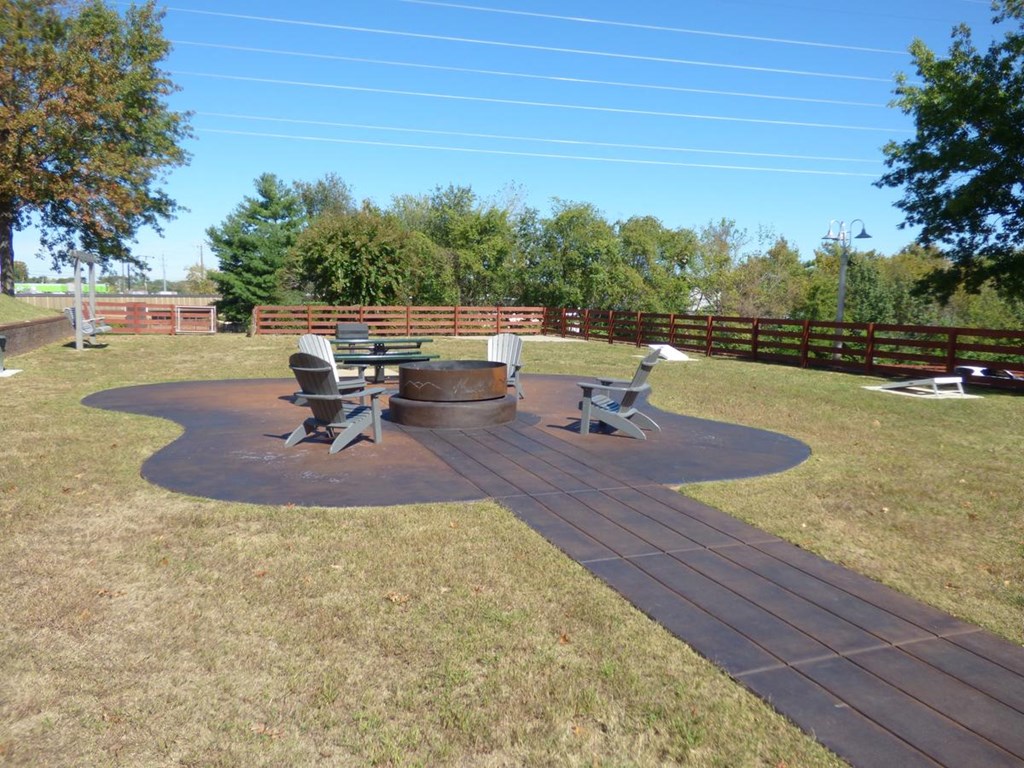 a patio with a fire pit and picnic table in a backyard