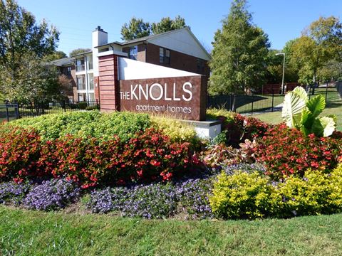 a sign for the knolls garden towers in front of a flower garden