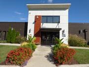 the front of a building with plants and a sidewalk