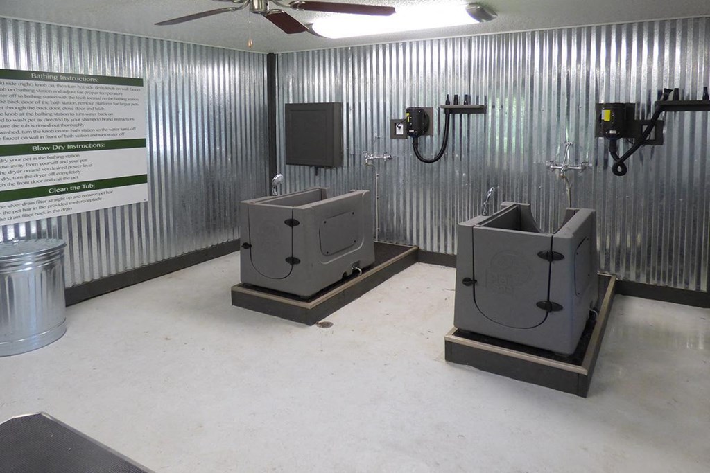 two urinals in a room with metal walls and a tv