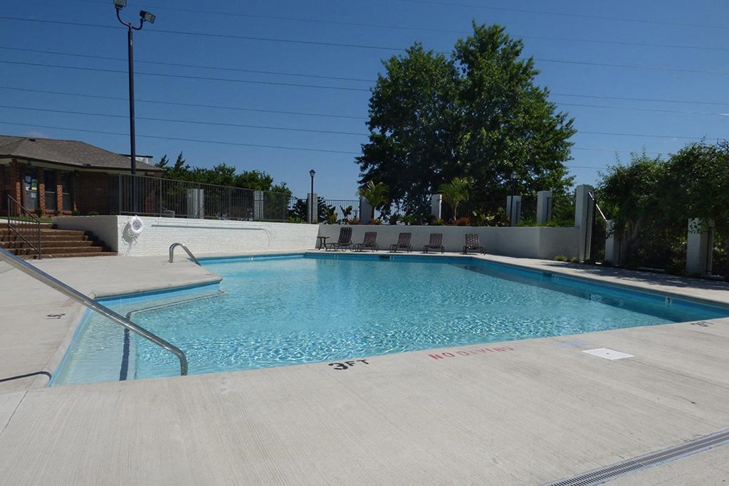 a swimming pool with chairs around it in front of a building