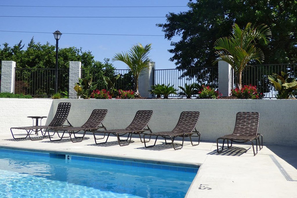 a group of lawn chairs sitting next to a swimming pool